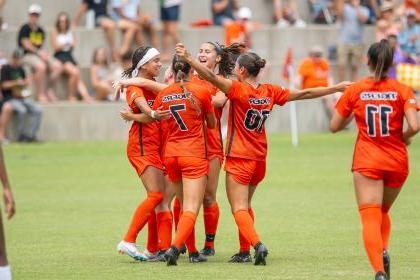 women's soccer players celebrate on the field